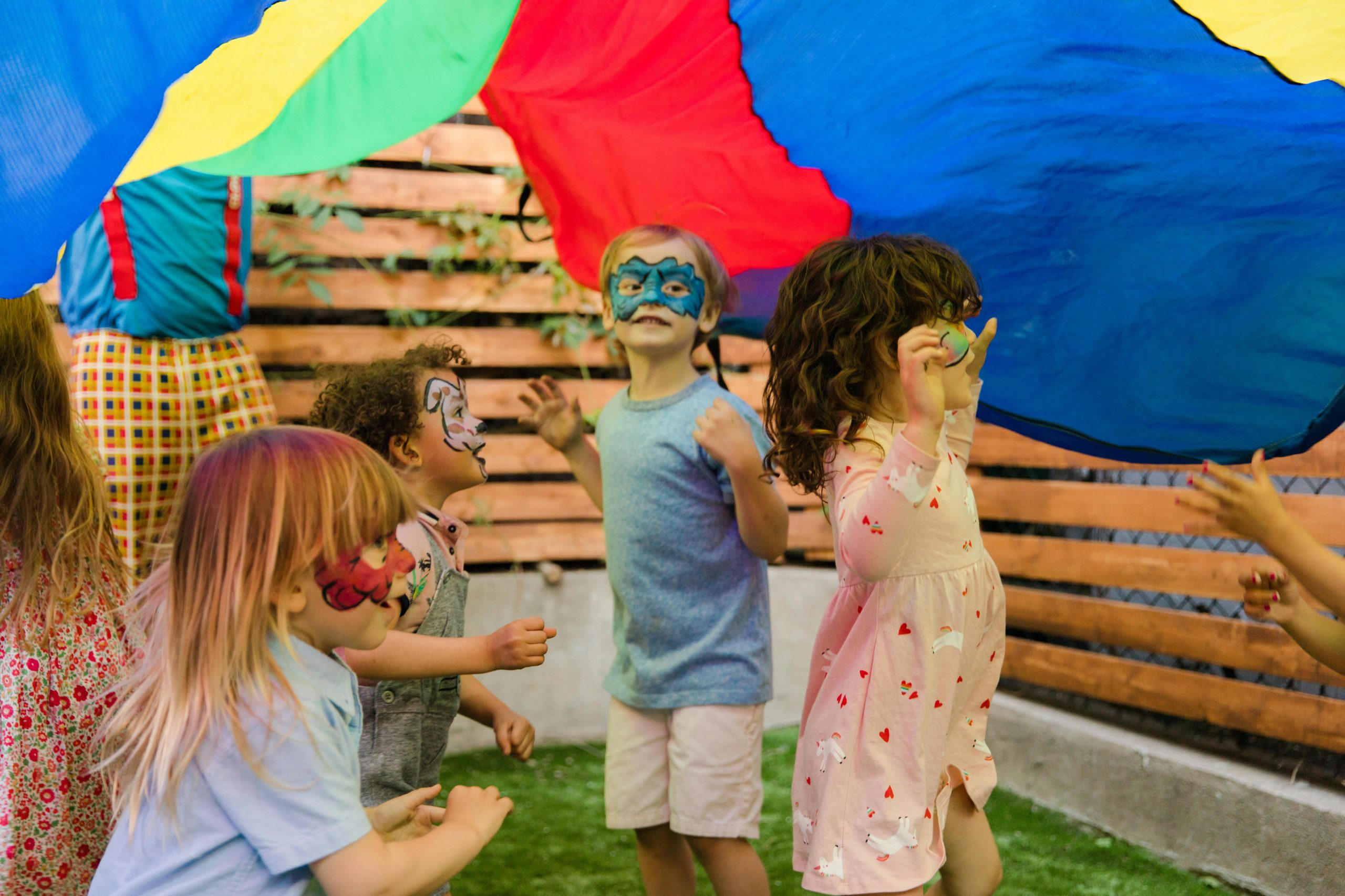 Children with face paint enjoying an outdoor party with vibrant colors and playful activities.
